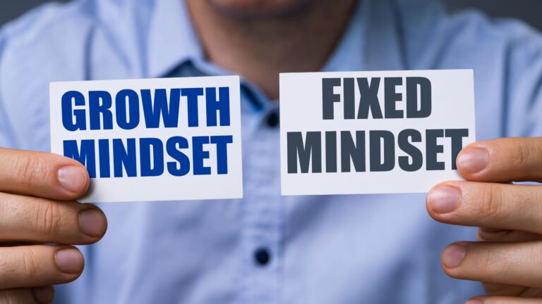 a person holds up two signs: growth mindset and fixed mindset