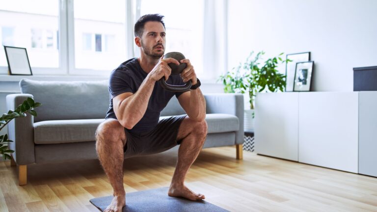 a young man does a quarter squat in his living room